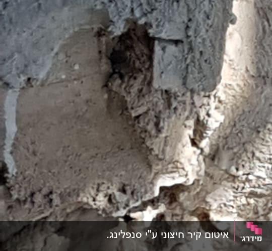 קיר בטון עם טיח מתקלף וחורים
